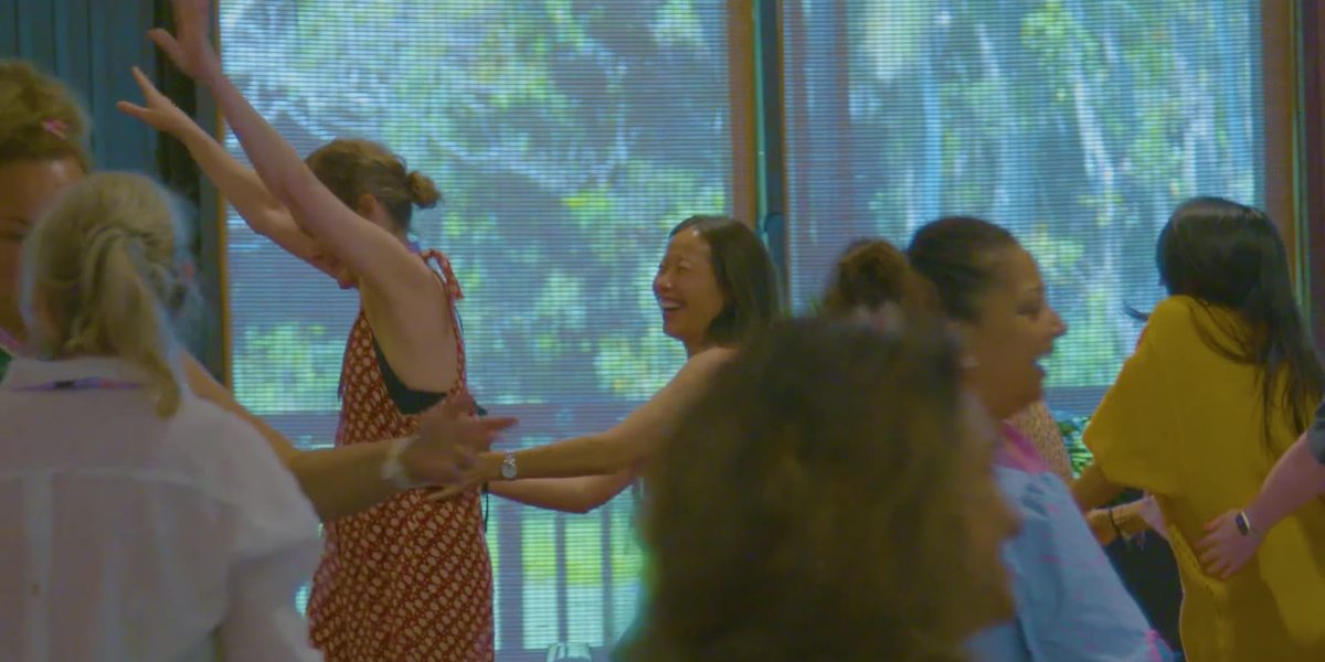 Women laughing and moving together at the Fiji 2022 gathering